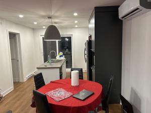 a dining room with a red table and a kitchen at Unactivated in Longueuil