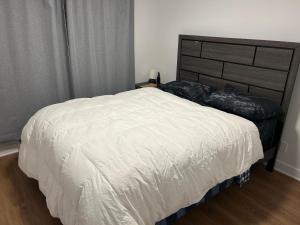a bedroom with a white bed with a black headboard at Unactivated in Longueuil
