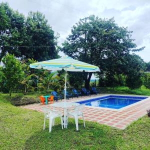 una mesa con sombrilla junto a la piscina en FINCA LA COLONIA en Buga