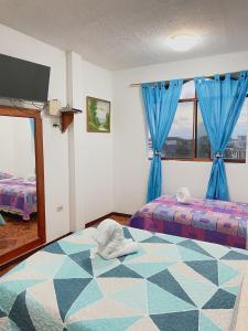 1 dormitorio con 2 camas, cortinas azules y TV en Moonlight, Galápagos en San Cristóbal