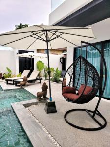 a patio with a hammock and an umbrella next to a pool at Villa Coco in Thalang