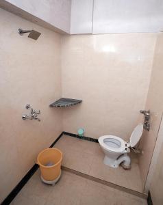 a bathroom with a toilet and a trash can at New Royal Hotel in New Delhi