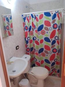 a bathroom with a toilet and a sink and a shower curtain at VIVIENDA TURISTICA GAIRA in Rodadero