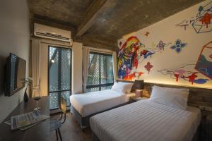 a bedroom with two beds and a painting on the wall at Cacha Hotel in Bangkok