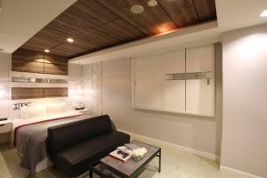 een slaapkamer met een bed, een bank en een tafel bij HOTEL KSEA (Adult Only) in Matsudo