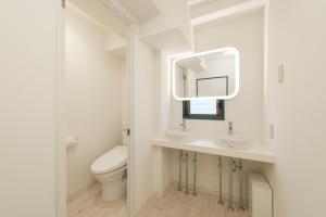 a white bathroom with a toilet and a mirror at KandO Hostel Ueno in Tokyo