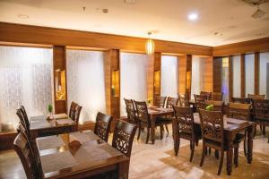 um restaurante com mesas e cadeiras de madeira e janelas em Hotel High Point em Tiruchchirappalli