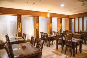 un restaurante con mesas y sillas de madera y ventanas en Hotel High Point, en Tiruchchirāppalli