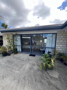 a house with glass doors and potted plants at Taipa Views Bed & Breakfast in Kaitaia