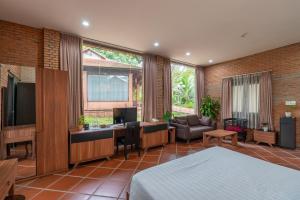 a bedroom with a bed and a desk with a television at Mekong Long Thanh Resort & Reststop in Ấp Thanh Nguyên