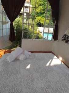 uma cama com duas almofadas num quarto com uma janela em Casa Sauces em Tepoztlán