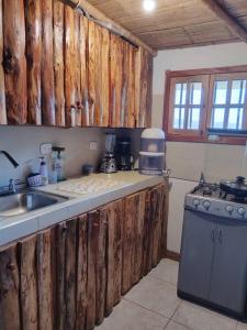 cocina con armarios de madera, fregadero y fogones en Cabaña Mirador del Otún, en Pereira