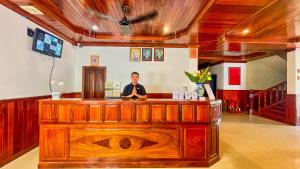 Ein Mann steht hinter einer Bar in einem Zimmer. in der Unterkunft Harmony Indochine d'Angkor in Siem Reap