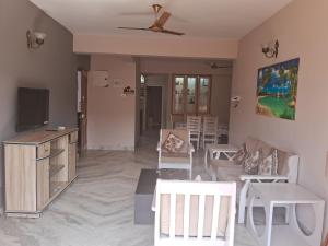Coconut Grove Holiday Apartment في فاكا: غرفة معيشة بأثاث أبيض وتلفزيون بشاشة مسطحة