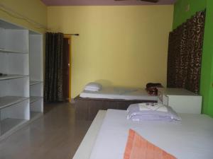 a room with two beds and a green wall at Prakriti neerh in Jyoti Gaon
