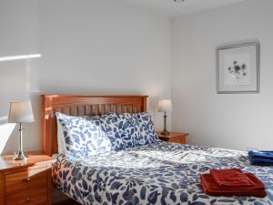 ein Schlafzimmer mit einem blauen und weißen Bett mit zwei Lampen in der Unterkunft The Longhouse At Threave in Castle Douglas