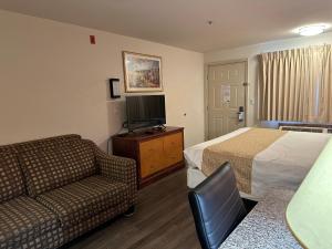 a hotel room with a bed and a couch and a tv at Econo Lodge Edmonds North Seattle in Edmonds