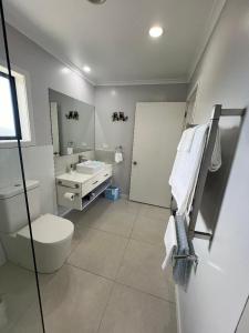 a white bathroom with a toilet and a sink at Taipa Views Bed & Breakfast in Kaitaia