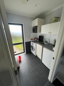 a kitchen with white cabinets and a washer and dryer at Taipa Views Bed & Breakfast in Kaitaia