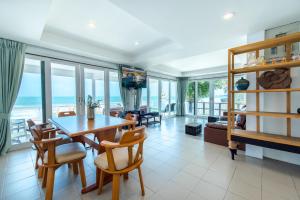 a living room with a table and chairs and the ocean at TheSkyCozy Beachfront in Cha Am