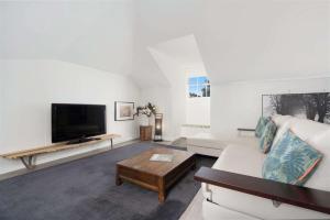 a living room with a couch and a flat screen tv at Myrtle Tree Lodge Leaves, Kangaroo Valley in Kangaroo Valley