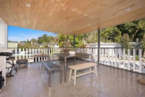 a patio with a table and benches on a deck at Myrtle Tree Lodge Leaves, Kangaroo Valley in Kangaroo Valley