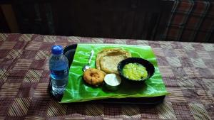 a green plate with food and a bottle of water at Achus Holidays in Munnar