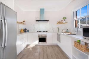 a white kitchen with white cabinets and a refrigerator at Myrtle Tree Lodge Flowers, Kangaroo Valley in Kangaroo Valley