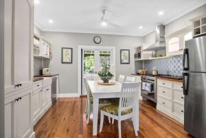 a kitchen with white cabinets and a table and chairs at Lemon Tree Cottage, Kangaroo Valley in Kangaroo Valley