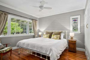a bedroom with a white bed and two windows at Lemon Tree Cottage, Kangaroo Valley in Kangaroo Valley