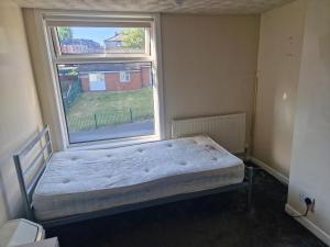 a bedroom with a bed in front of a window at Cozy Bedroom in Spacious House Manchester in Rochdale