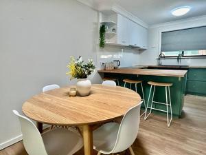 UtakarraにあるThe Wildflower- Luxury Home Stayのキッチン(木製テーブル、白い椅子付)
