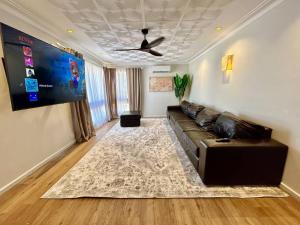 ein Wohnzimmer mit einem schwarzen Ledersofa und einem Teppich in der Unterkunft The Wildflower- Luxury Home Stay in Utakarra