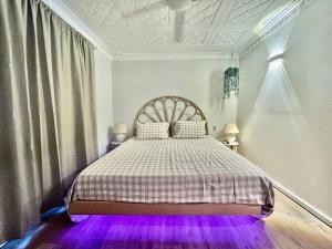 UtakarraにあるThe Wildflower- Luxury Home Stayのベッドルーム1室(紫色の照明付きのベッド1台付)