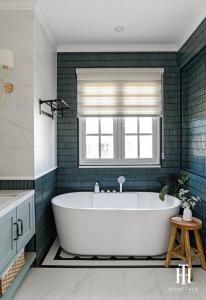 y baño con bañera y azulejos verdes. en Villa 3PN Novaworld Phan Thiết, en Phan Thiet