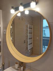 La salle de bains est pourvue d'un miroir rond et d'un lavabo. dans l'établissement Happiness Apartman, à Kecskemét 52 autres photos