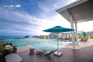 a patio with chairs and an umbrella and a swimming pool at Villa 3PN Novaworld Phan Thiết in Phan Thiet