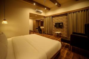 a hotel room with a bed and a television at Eko Resort - Jim Corbett in Belparāo