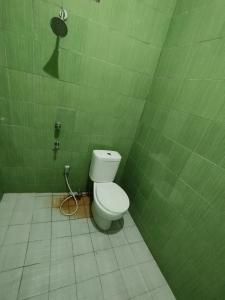 a bathroom with a toilet in a green wall at OYO 93343 Sukma Residence in Palangkaraya