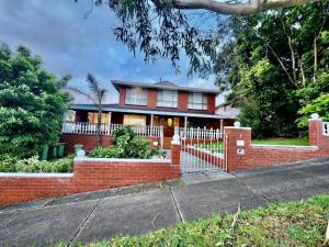 a red brick house with a white fence at Cozy and nice stay with sunset view! in Mooroolbark