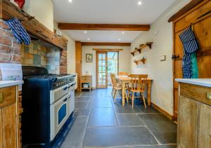 a kitchen with a stove and a table with chairs at Chestnut Cottage in Manorbier