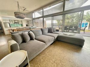 a living room with a gray couch and a kitchen at Margaret River Beach Houses in Gnarabup