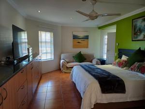 a bedroom with a bed and a tv and a couch at Cowrie Lodge at Cove Rock Country Estate in East London