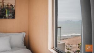 een slaapkamer met een raam met uitzicht op het strand bij Arrendamiento Peru in Lima