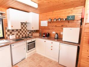 a kitchen with white cabinets and a wooden wall at 2 bed in Launceston TWIME in Saint Clether