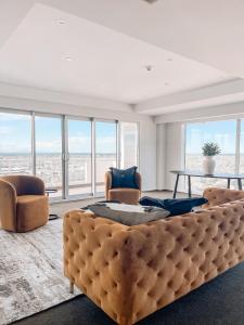 a room with a large bed and chairs and windows at Sub-Penthouse on Gloucester - Highest rental in the South Island in Christchurch