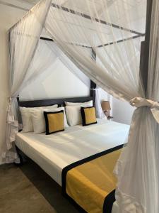 a bedroom with a canopy bed with yellow and white pillows at Medusa Bungalow - Galle in Galle