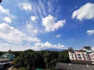 um céu azul com nuvens, árvores e edifícios em Sasima House em Chiang Mai