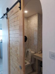 a bathroom with a toilet and a wooden door at Sasima House in Chiang Mai