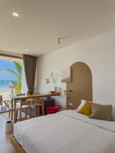 Schlafzimmer mit einem Bett und einem Schreibtisch mit Blick auf den Strand in der Unterkunft lovelytheroom in Ko Lanta